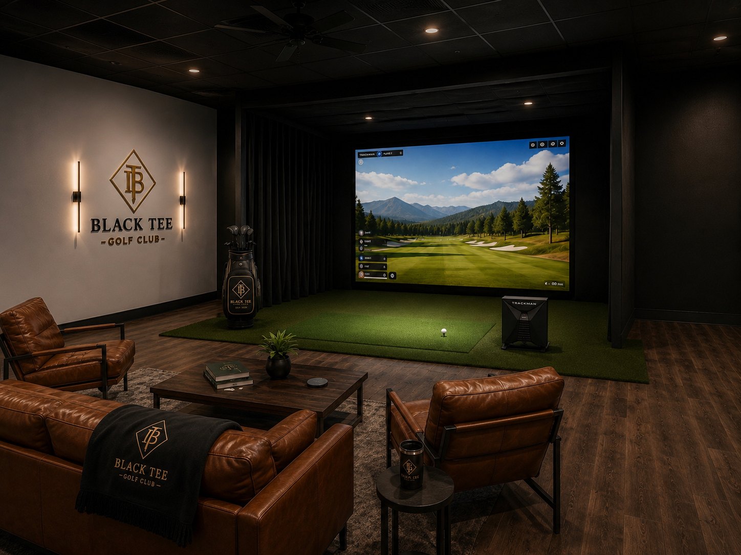 Black Tee Golf Club simulator bay with the ivory logo wall on the left, leather chairs and a coffee table in the foreground and a mountain course on the screen
